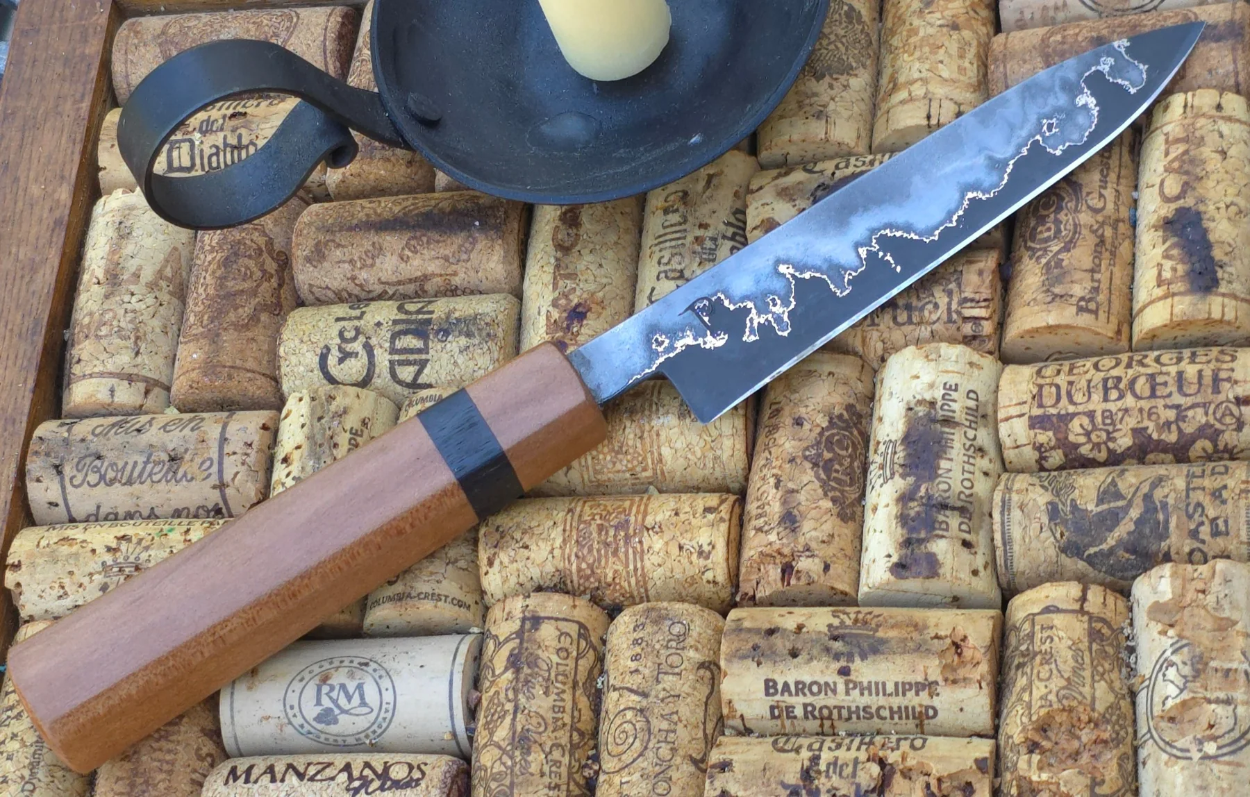 Small hand-forged knife displayed over vintage wine corks