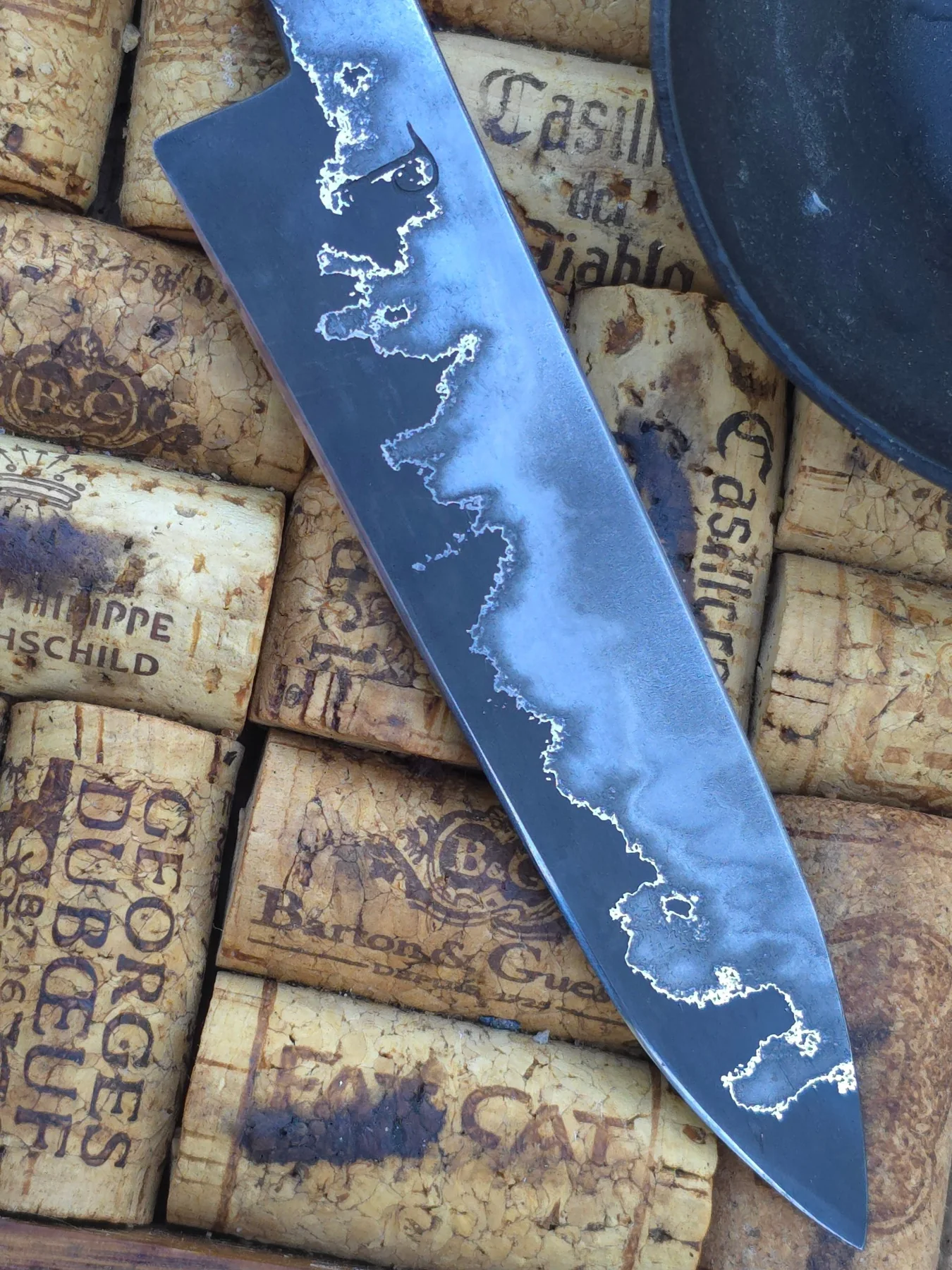 Close view of etched blade and maker mark over vintage wine corks