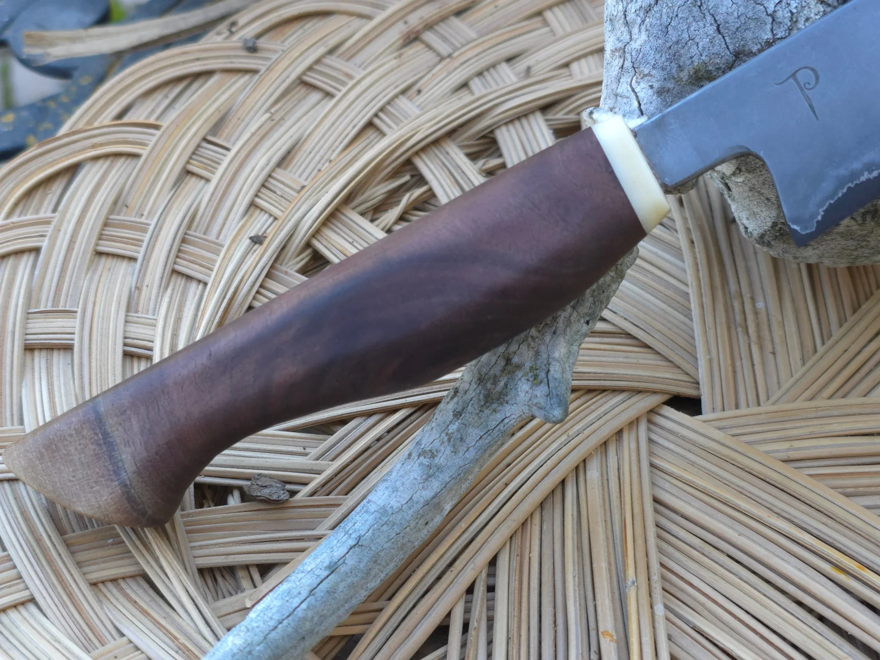 Sculpted wood handle beside antler and woven natural material