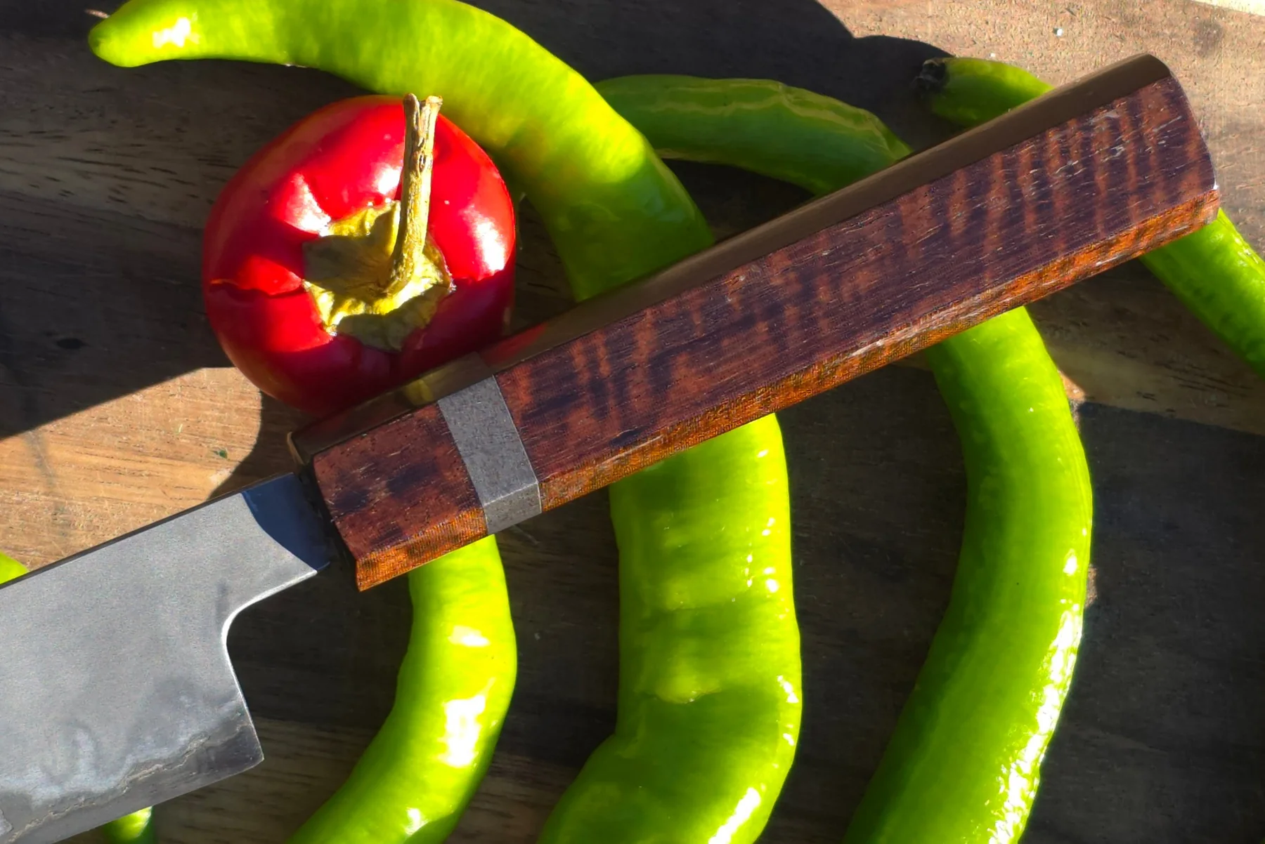 Wooden knife saya among red and green peppers